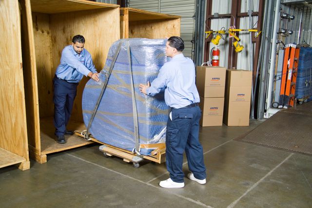 Movers loading a wrapped item into a wooden storage vault