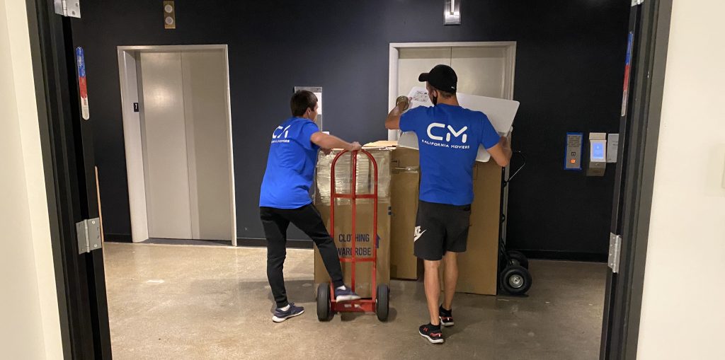 Halo California Movers crew moving wardrobe boxes and furniture through a building elevator lobby