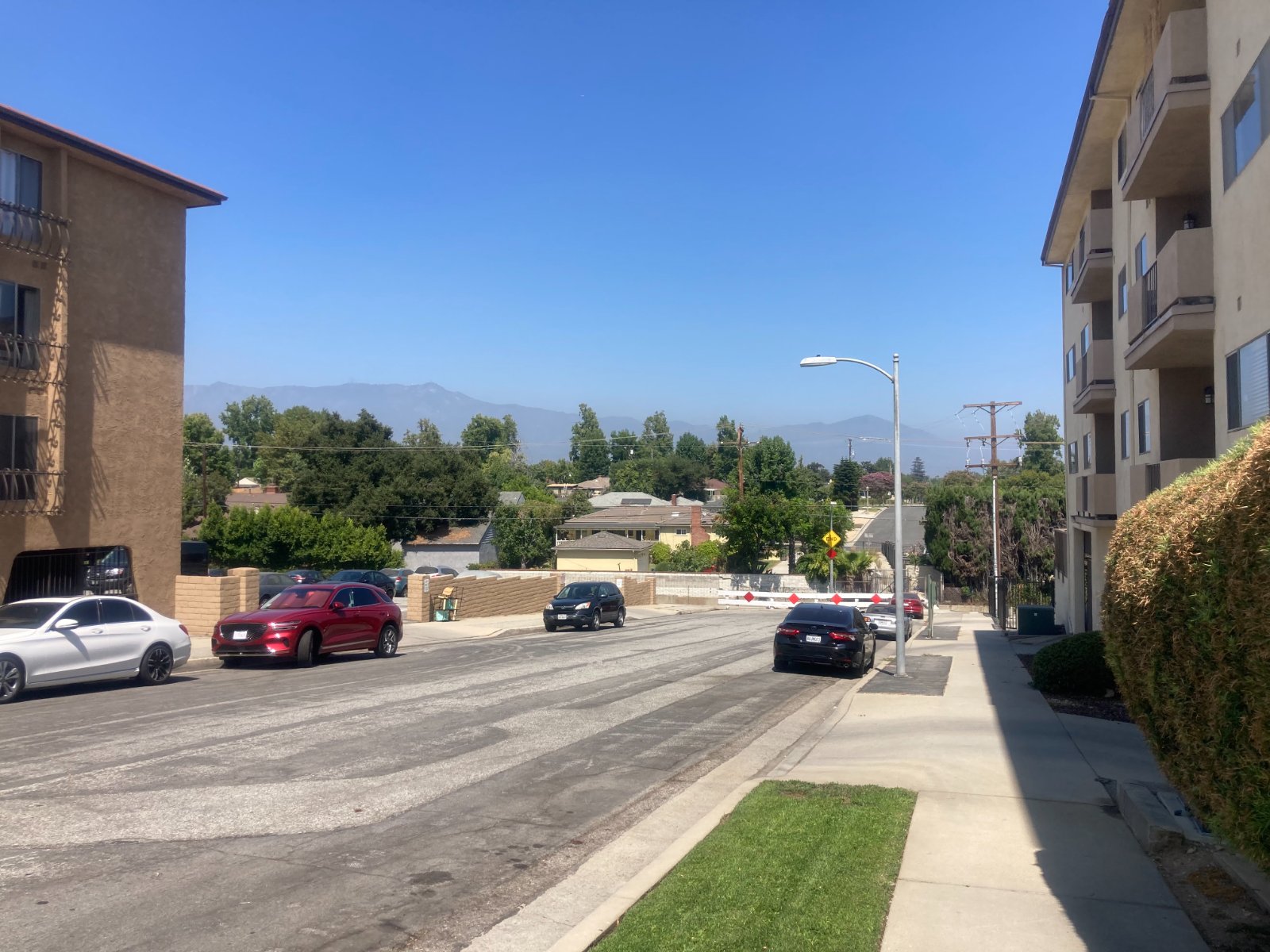 Residential street in Alhambra, California, with parked cars and the San Gabriel Mountains behind