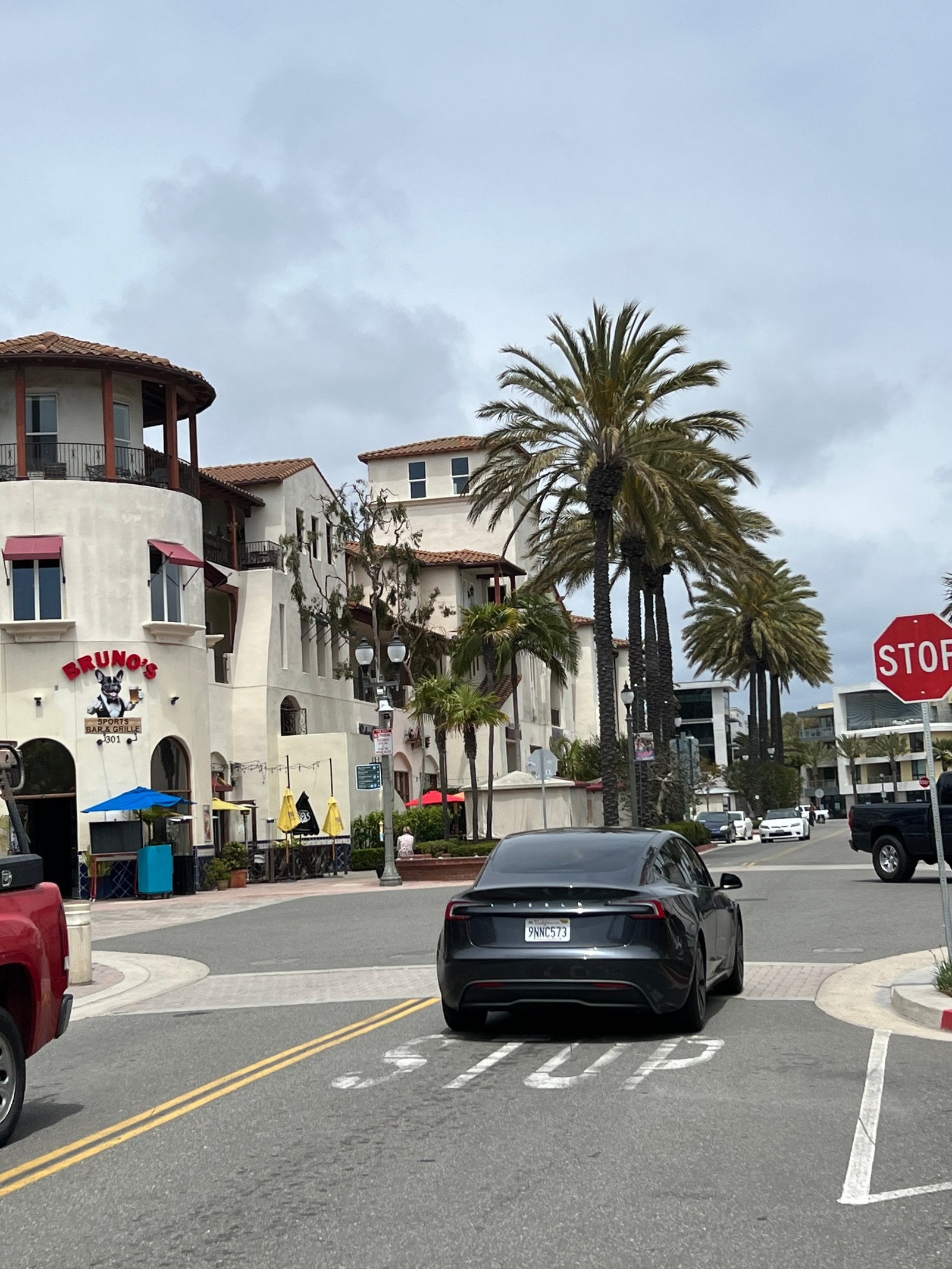 Street corner with mixed-use buildings and palm trees in downtown Huntington Beach, California, where California Movers USA confirms the legal truck position