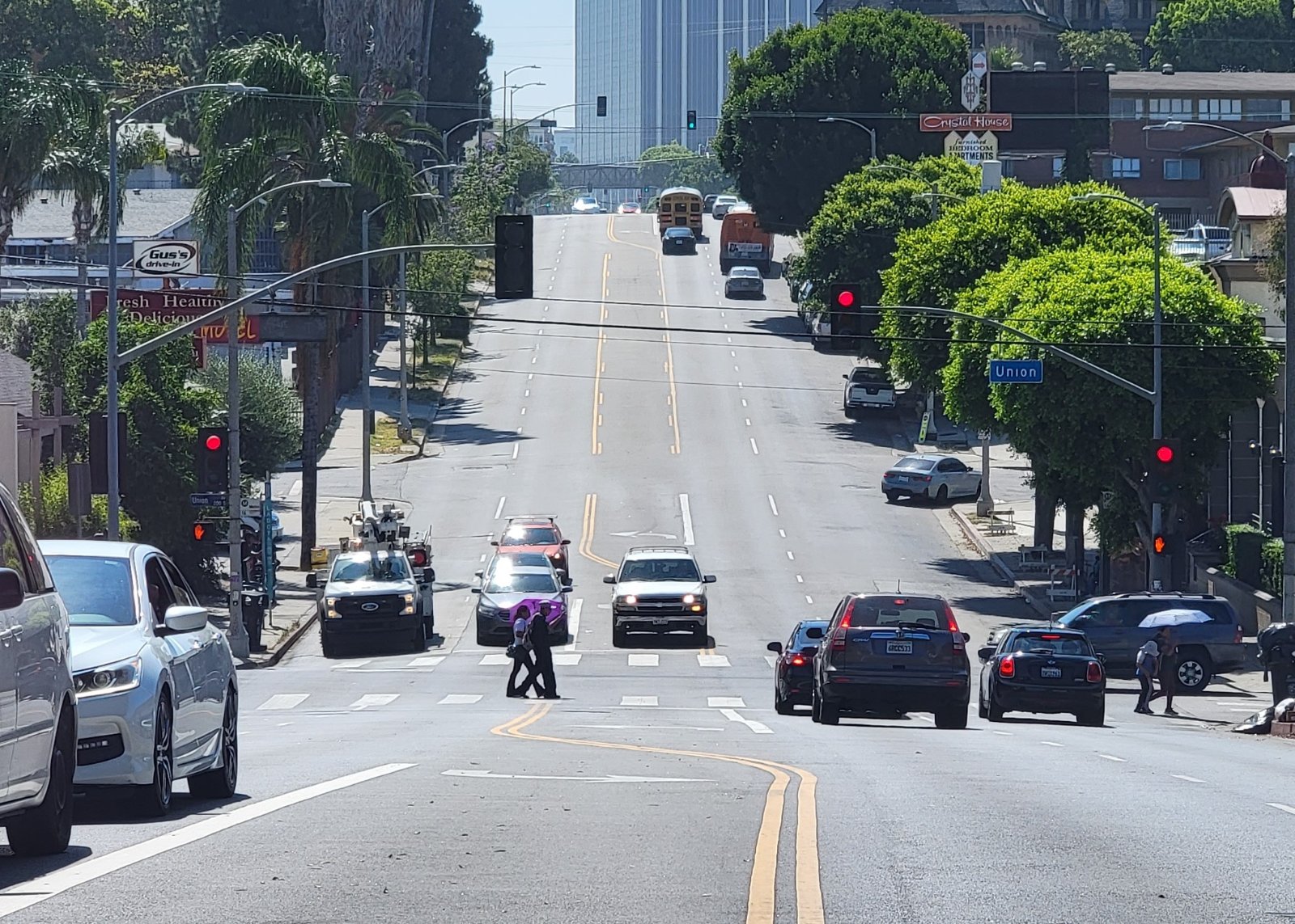Los Angeles street with cars parked along both curbs and the downtown skyline ahead, where Halo California Movers confirms the legal truck loading position