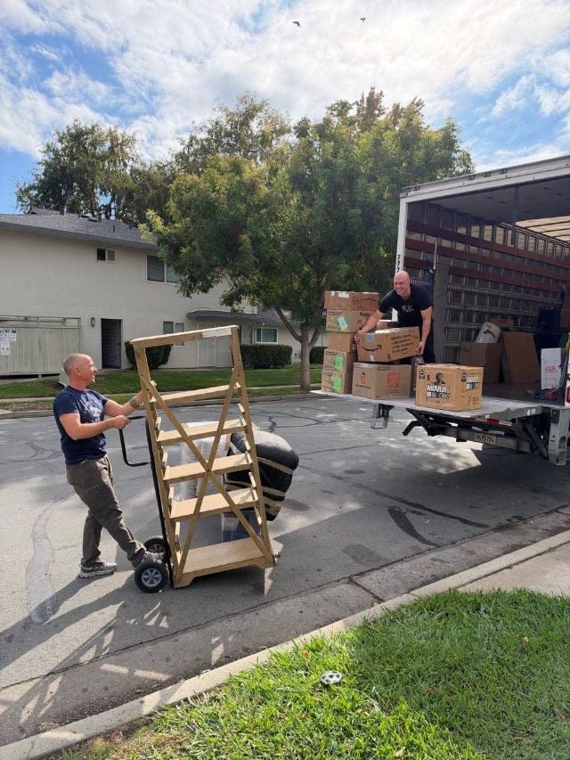 Two California Movers crew members loading boxes onto the truck liftgate
