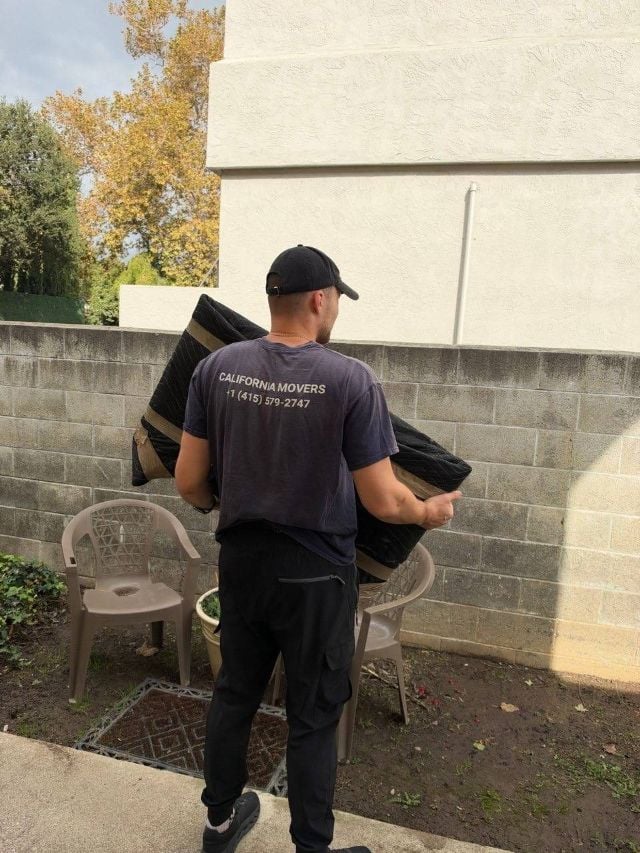 Mover carrying furniture wrapped in a moving blanket